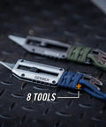 Close-up of two Prybrid X EDC Multitool Pocket Knives with retractable box cutter blades and paracord wraps on metal surface.