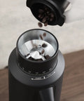 Dope Single Dose Electric Coffee Grinder Featuring 64Mm Titanium Flat Burrs And Stepless Adjustment To Nail Your Flavor Packed Espresso Routine In Sleek Black Finish with coffee beans pouring in.