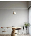 Industrial Marble Pendant Light Fixture Chandeliers in a modern dining area with wooden table and plants.