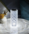 Lit Crystal Diamond Portable Table Lamp With 3 Color Touch Control on a white surface, reflecting light patterns.