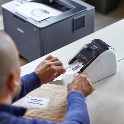 Man using Turbo Fast Label Printer For Shipping And Address Labels With Auto Cutter, Crisp 300 DPI Black And Red Output, Works With DK-2251 Label Rolls For Packages And Envelopes, Renewed to print shipping label