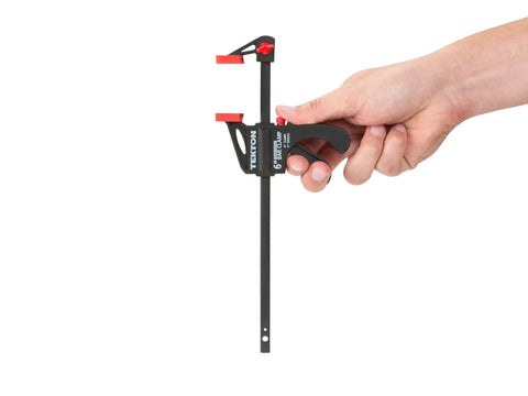 Hand holding 6 Inch Ratchet Bar Clamp And 9 Inch Spreader with Quick Release Jaw, continuous trigger, reinforced nylon, soft jaw pads.