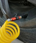 Heavy Duty 5 In 1 Universal Quick Industrial Air Coupler With Dead Simple Setup And Knockout Durability For 1/4 Inch Female Npt Air Compressor Fittings Quick Connect Accessory In Bold Red attached to a yellow coil hose for tire inflation.