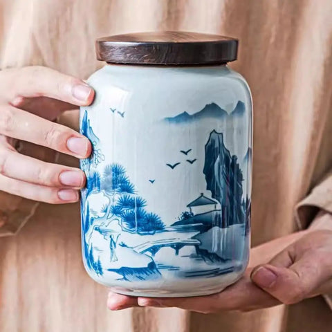 Top Shelf Airtight Ceramic Tea Canister Keeping Freshness Locked Inside Retro Blue And White Landscape Vibes held by hands.