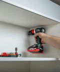 Hand holding Badass 18 Volt Cordless Brushless Drill Driver delivering 60 Newton Meters of torque, drilling into a shelf.