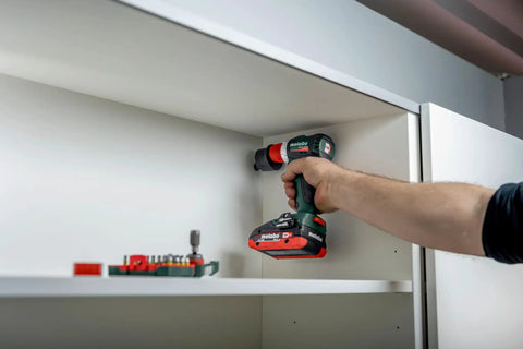 Hand holding Badass 18 Volt Cordless Brushless Drill Driver delivering 60 Newton Meters of torque, drilling into a shelf.