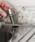 Heavy Duty Universal Faucet Hose Guide In Brushed Nickel being installed into a sink's mounting hole next to granite countertop.