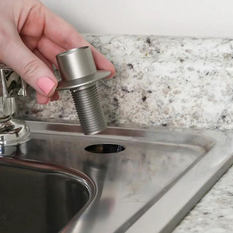 Heavy Duty Universal Faucet Hose Guide In Brushed Nickel being installed into a sink's mounting hole next to granite countertop.