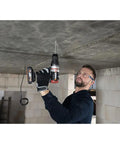Man using a Brushless Cordless Hammer Drill With Two 20 Volt Batteries And Active Hammer Action for concrete overhead.