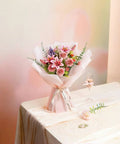 Bouquet with pink lilies and roses on a table with a champagne glass, ideal for home decor and special occasions.