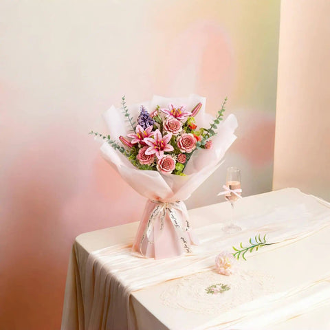Bouquet with pink lilies and roses on a table with a champagne glass, ideal for home decor and special occasions.