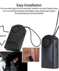 Ultra Loud 120dB Door Sensor Alarm For Home, Travel And Hotels, Touch, Vibration And Magnet Detection For Kids Safety, Luggage, Backpack, And Security, Instant Alerts When Door Opens, black portable unit hanging on door handle