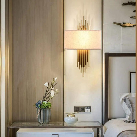 Swanky Modern Fabric Wall Sconce Featuring High Quality Shade for Soft Ambient Lighting Perfect for Bedroom Hallway and Living Room Space Super Chic Decor Piece with Eye Protection Rays and Minimalist Design That Really Slays Your Home Vibe, mounted beside nightstand with decorative plants.