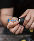 Electric handheld drill with blue twist drill bit secured in metal chuck in close-up view.