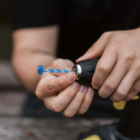 Electric handheld drill with blue twist drill bit secured in metal chuck in close-up view.