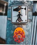 Red cast iron hand wheel on a metallic pole with a pedestrian crossing sign above