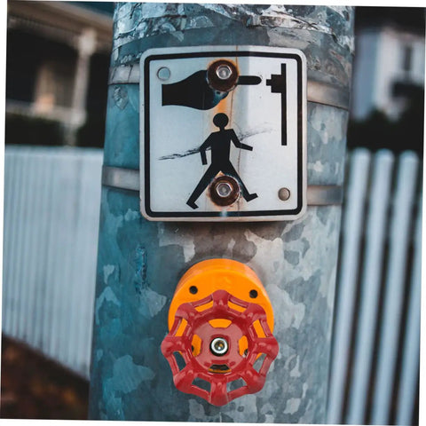 Red cast iron hand wheel on a metallic pole with a pedestrian crossing sign above