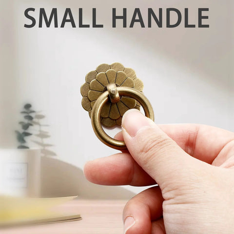 Hand holding antique brass ring pull with flower discs, small size, part of Set Of Six Antique Brass Ring Pulls For Drawers And Cabinets.