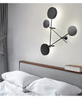 Top Shelf Round Led Wall Sconce Lighting For Bedroom Bedside Decor Featuring Smooth 360 Degree Rotation Matte Black Iron Industrial Loft Fixture Serving Clean Soft Glow on a wall above a gray upholstered bed.
