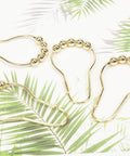 Gold Stainless Steel Shower Curtain Hooks Set Of 24 with 5 bead rollerball design on tropical background