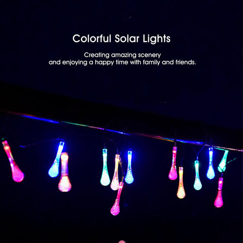 Colorful solar lights hanging in darkness, emitting pink, blue, and green hues, creating a vibrant nighttime scene.