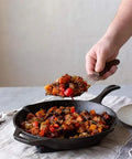 Person serving vegetables from 10 Inch Preseasoned Cast Iron Skillet With Ergonomic Handles, Pour Spouts, And Durable Build