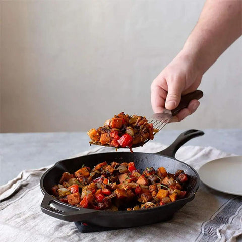 Person serving vegetables from 10 Inch Preseasoned Cast Iron Skillet With Ergonomic Handles, Pour Spouts, And Durable Build