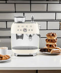 Top Shelf Semi Automatic Espresso Machine With Built In Conical Burr Grinder Dual Thermoblock Heating Precision Controls And Authentic 1950s Retro Vibe In Smooth Cream Finish on kitchen counter next to pastries.