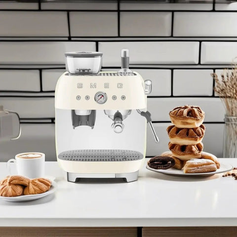 Top Shelf Semi Automatic Espresso Machine With Built In Conical Burr Grinder Dual Thermoblock Heating Precision Controls And Authentic 1950s Retro Vibe In Smooth Cream Finish on kitchen counter next to pastries.