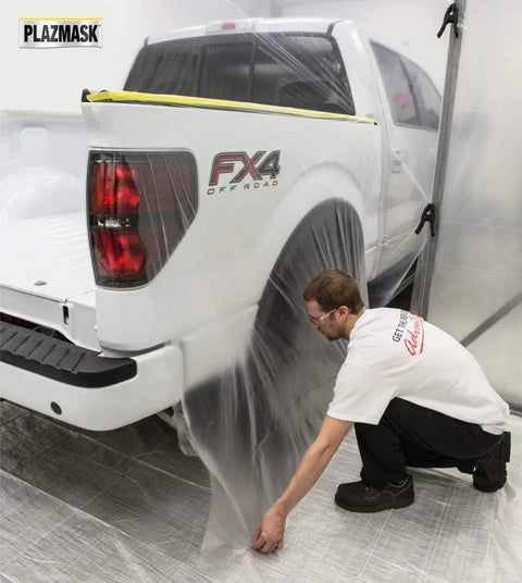 Person applying Pre Taped Masking Film With Three Quarters Inch Tape For Auto Body Protection on pickup truck in a workshop