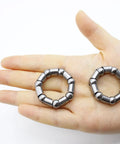 Hand holding 4 Piece Bike Ball Bearing Retainer Set With 8mm Balls, 38mm Outer Diameter, 24mm Inner Diameter, 5 By 16 Inch Ball Size.