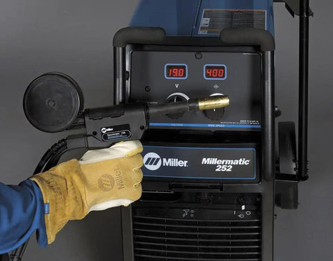 Smooth Rolling MIG Flux Core Welding Rig Tackles Mild Steel And Aluminum Like A Champ Dual Voltage 208 230VAC close-up of Miller welder settings with glove