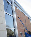 Person cleaning high windows with an extendable squeegee tool.