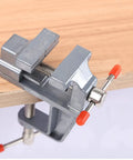 Rock Solid Mini Bench Vise, Clamp On Table Workstation Setup, heavy-duty jaws clamping onto wood for stable woodworking.