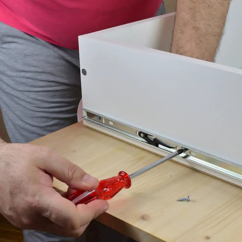 Rock Solid 14 Inch Keyboard Drawer Slides With Smooth Ball Bearings being installed in a white drawer using a red screwdriver.