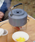 Two Point Two Liter Camping Kettle For Open Flame And Stove, fast boil, lightweight, anti-scald handle, on a table outdoors
