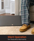 New And Improved Flat Panel Space Heater For Home And Office Portable 150W Heater beside a seated person in plaid pants.