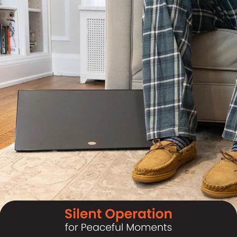 New And Improved Flat Panel Space Heater For Home And Office Portable 150W Heater beside a seated person in plaid pants.