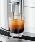 Top Tier Automatic Espresso Machine Bundle In Piano White With Glass Milk Container And Clearyl Smart Filter Cartridge For Seamless One Touch Operation And Premium Daily Grinds preparing espresso in a glass.