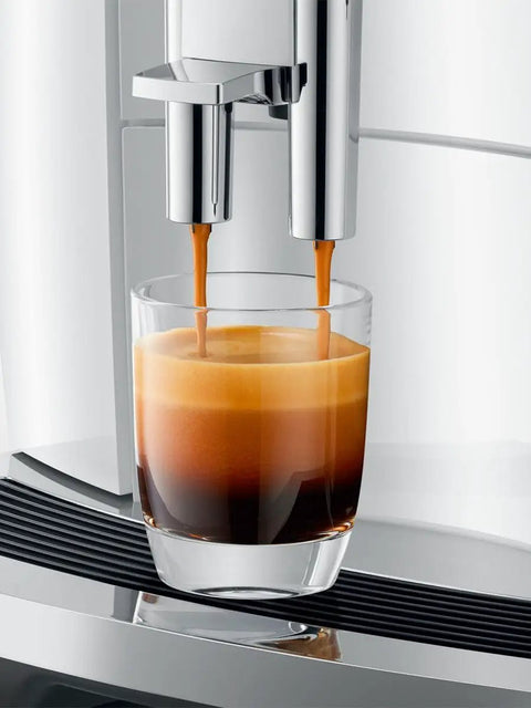 Top Tier Automatic Espresso Machine Bundle In Piano White With Glass Milk Container And Clearyl Smart Filter Cartridge For Seamless One Touch Operation And Premium Daily Grinds preparing espresso in a glass.