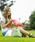 Woman sitting on grass with Waterproof Drawstring Storage Bags Set Of Five Made From PE Plastic Great For Travel Gym Swim Gear And Laundry Organization Quick Access And Easy Packing For Home Or On The Go
