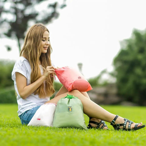 Woman sitting on grass with Waterproof Drawstring Storage Bags Set Of Five Made From PE Plastic Great For Travel Gym Swim Gear And Laundry Organization Quick Access And Easy Packing For Home Or On The Go