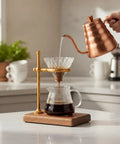 Premium Heavy Duty Copper Alloy Pour Over Coffee Dripper Stand With Weighted Stable Cone Filter Holder For Smooth Top Shelf Brewing Station Setup Game Changer, angular view with copper kettle pouring coffee.