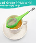 Long Handled Tea Infuser With Fine Mesh Strainer And Built In Plunger Reusable Loose Leaf Coffee Filter dual compartment steeper in green resting on a mug