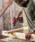 Man using 2 Tool Drill Driver And Circular Saw Combo Kit with Brushless 20V drill driver on wooden frame inside workshop.