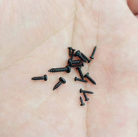Black Carbon Steel Tiny Phillips Pan Head Self Tapping Screws in hand, various sizes for electronics precision repairs.