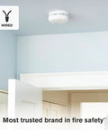 Rock Solid Hardwire Smoke Alarm Featuring Dual Sensor Tech and Precision Detection mounted on a ceiling in a light blue room.