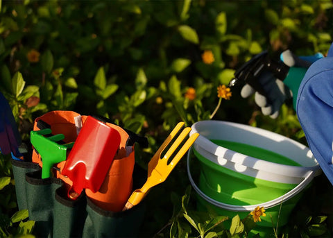 Kids Metal Garden Tool Set For Little Green Thumbs With Real Shovel Rake Fork Trowel Sun Hat Apron Gloves Tote Bag Sprayer and Bucket Educational Outdoor Garden Gift. Image shows colorful metal tools with wooden handles in a green tote bag, a sprayer, and a green bucket for gardening.