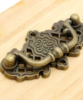 Image of a vintage antique brass bail pull handle mounted on wood, features a decorative hollowed pattern, part of 4 pack, 2.6x1.5 inches, zinc alloy.