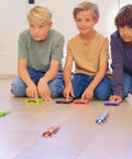 Boys racing Pocket Size Racecar Launcher With Real Rubber Tires For High Speed Racing on wooden floor indoors, toys in motion
